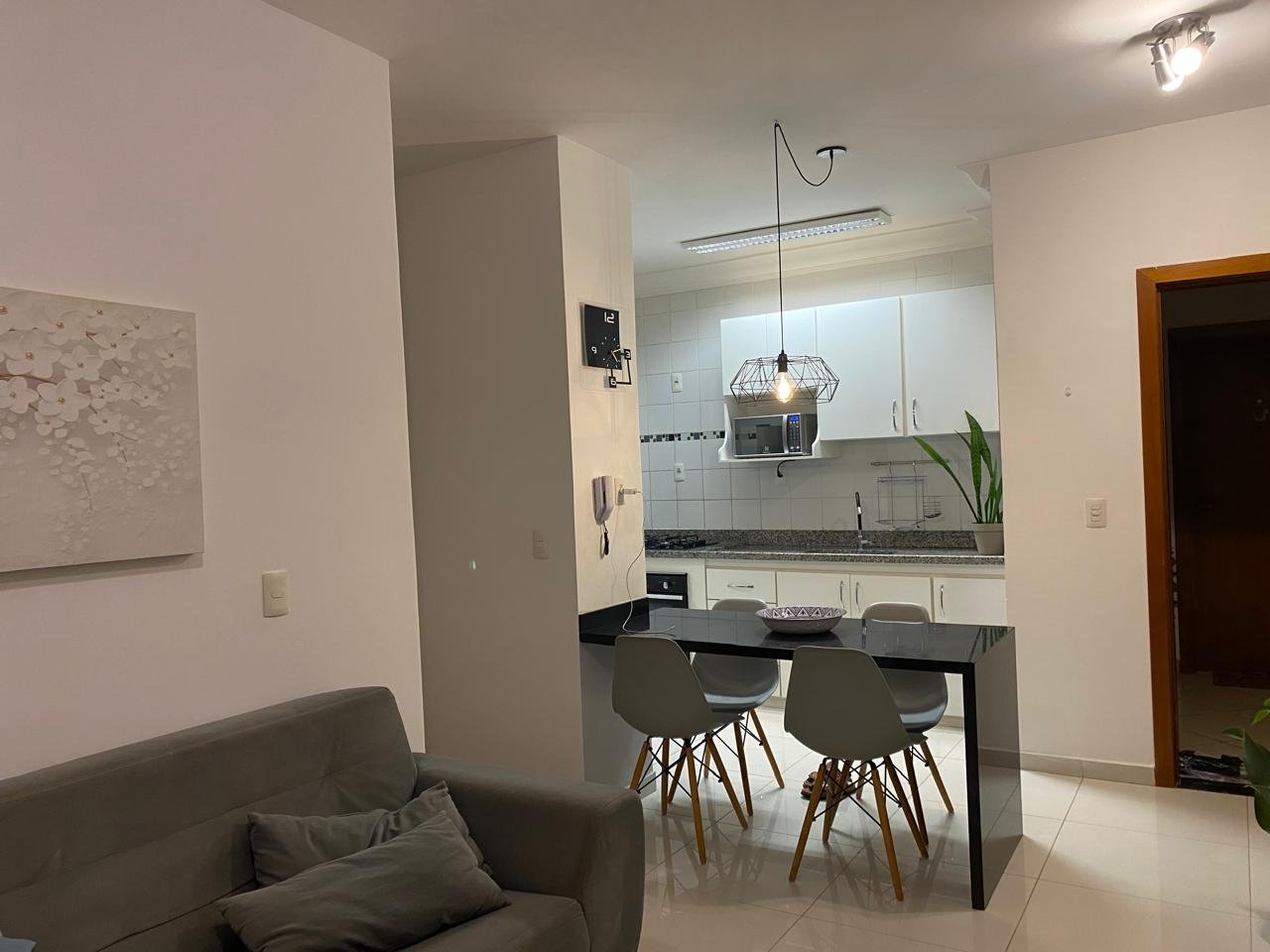 Sala de estar de um apartamento decorado pela melugga, com sofá, iluminação quente e ambientes integrados
